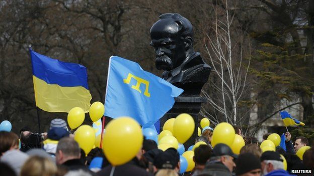 Pro-Ukrainian supporters wave flags near a monument to Ukrainian poet Taras Shevchenko at a rally in Simferopol