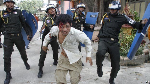 An injured Cambodian worker escapes from riot police in the compound of a Buddhist pagoda in Phnom Penh, Cambodia, Tuesday, Nov. 12, 2013