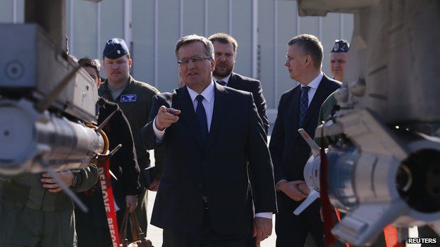 Polands President Bronislaw Komorowski points at missiles placed under a wing of a F-16 fighter jet as he visits the Lask airbase in central Poland March 11, 2014