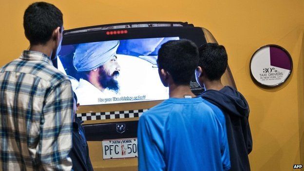 People watch a display about taxi drivers at the Smithsonian Museum of Natural History