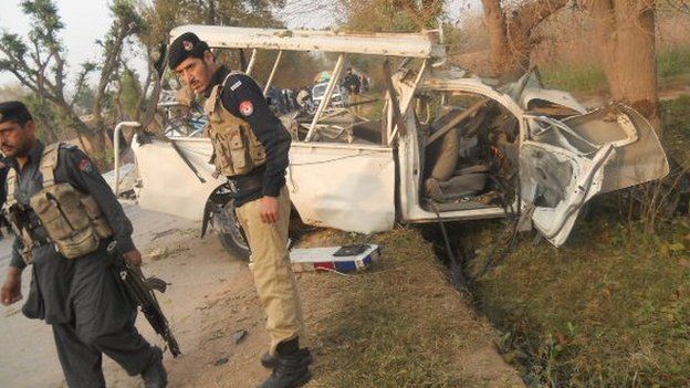 Security forces around the wreckage of Abdul Haq vehicle wrecked by a road bomb