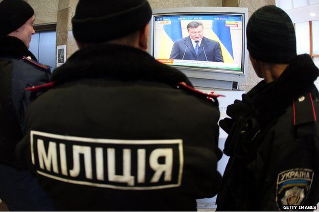 Police officers guarding the regional state administration building in Donetsk watch the televised speech of former Ukrainian President Viktor Yanukovych during his press conference in the Russian city of Rostov-on-Don on March 11, 2014.