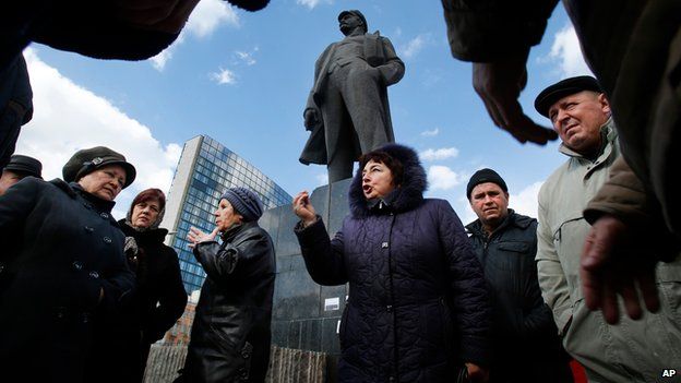 People discuss developments in front of Lenin statue in Donetsk, Ukraine, on 12 March 2014