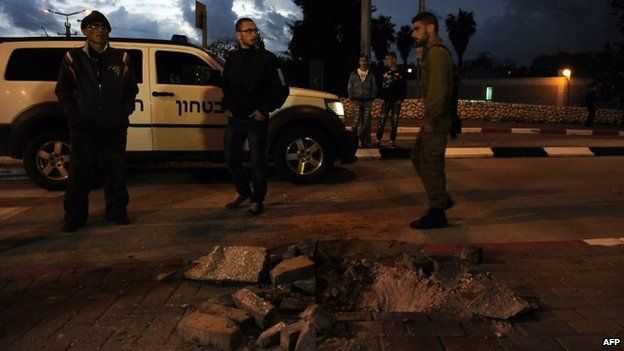 Israelis inspect the damage done by a rocket to a road in the town of Sderot (12 March 2014)