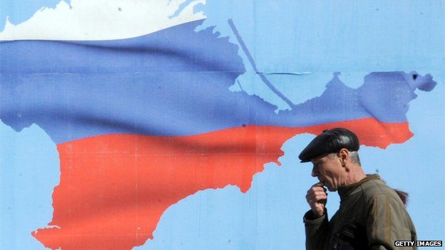 Man walks past poster of Crimea with colours of the Russian flag in Simferopol on 13 March 2014