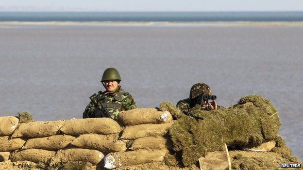 Ukrainian servicemen stand guard at a check point near a village in Kherson region, March 15