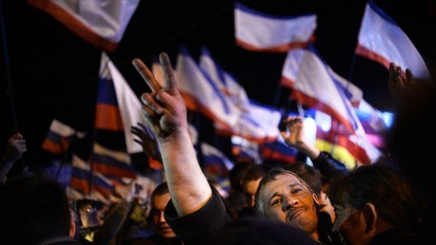A Crimean man makes the victory sign as he celebrates in Simferopol's Lenin Square on 16 March 2014 after exit polls showed that about 93% of voters in Ukraine's Crimea region supported union with Russia
