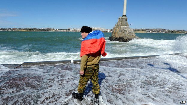 Pro-Russian self-defence activist wearing a Russian flag as he walks on Sevastopol embankment on 17 March 2014.