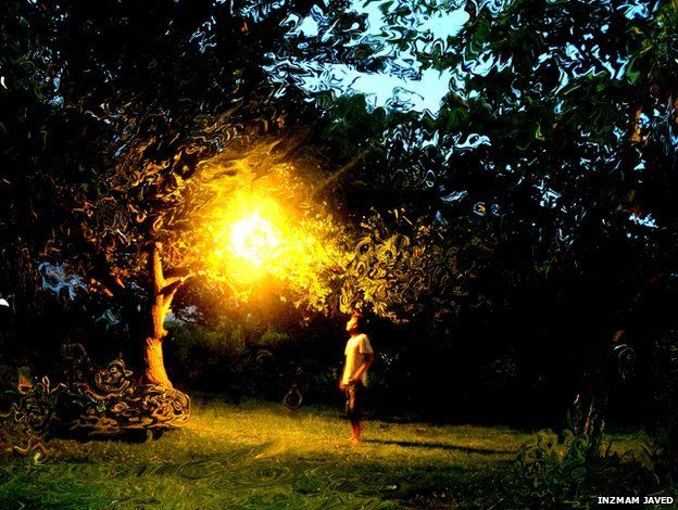 A man stands under a light in a tree-filled garden. A photographic trick creates an impression that the scene is being viewed underwater