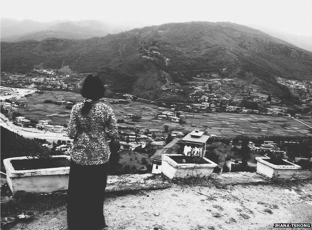 Woman stares out at view of mountain and houses beneath