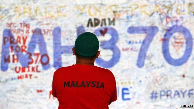 A man stands in front of a board with messages of hope and support for the passengers of the missing Malaysia Airlines MH370 at the departure hall of the Kuala Lumpur International Airport, 17 March 2014