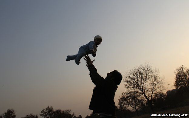 A man plays with a baby, throwing him in the air