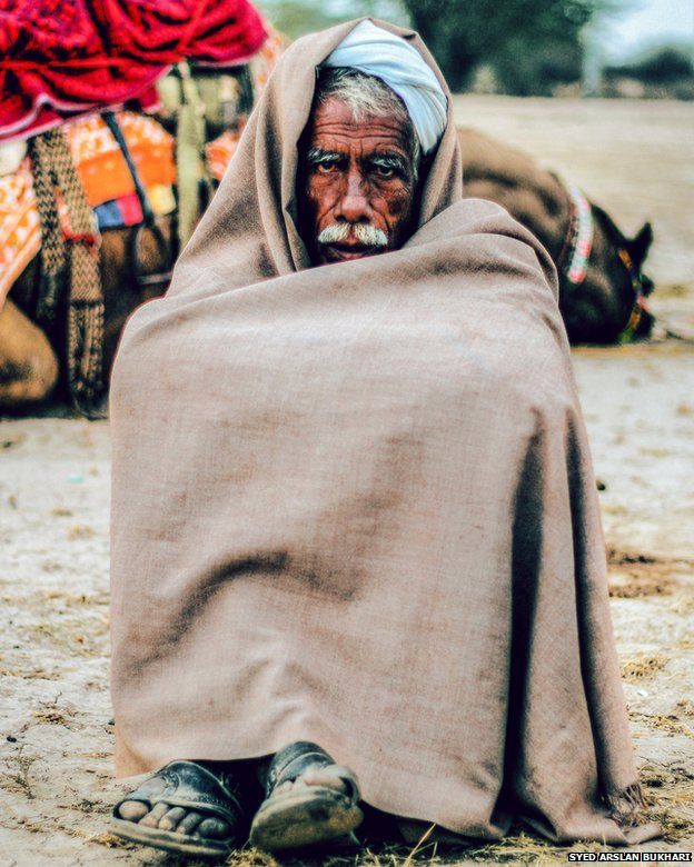A man wrapped in a blanket and sitting on the floor