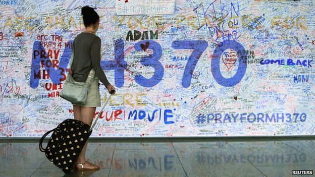 A woman looks at messages of support left for family members and passengers on board the missing Malaysia Airlines Flight MH370 at the Kuala Lumpur International Airport on 18 March 2014