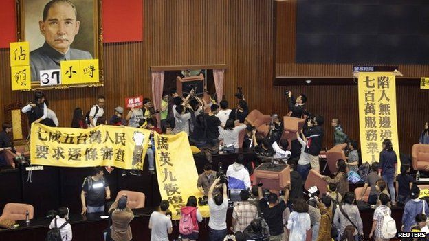 Students and protesters hold banners and chairs inside Taiwan's legislature in Taipei on 18 March 2014