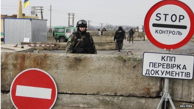 A Ukrainian soldier is seen at a checkpoint at the road near a Crimea region border 9 March 2014