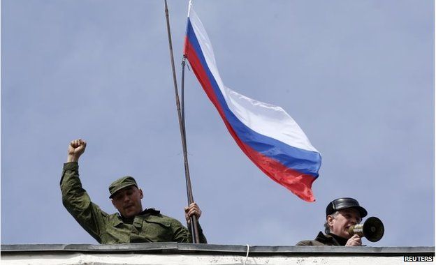 A man holds a Russian flag on the roof of the naval headquarters in Sevastopol on 19 March 2014