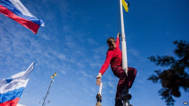 Pro-Russian activist takes down Ukraine's flag at Ukraine's navy HQ in Crimea on 19 March 2014