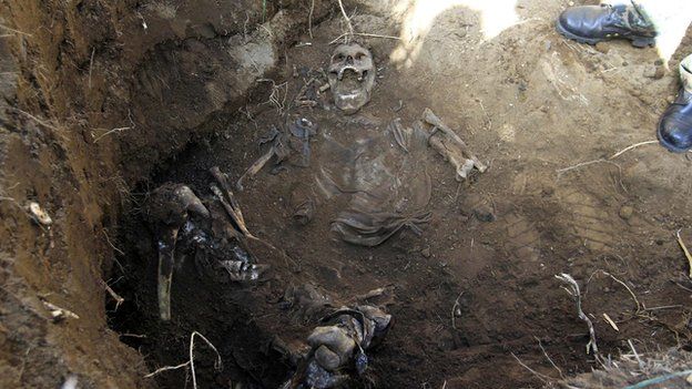 A forensic technician stands next to the remains of a person