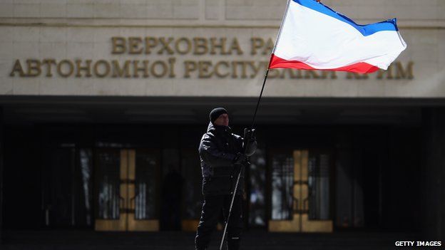 A man flies the Crimean flag outside the Crimean parliament in Simferopol