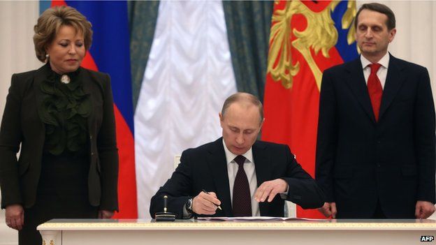 Vladimir Putin (C) signs a law on ratification of a treaty making Crimea part of Russia, during a ceremony in the Kremlin, with Valentina Matviyenko (L), the speaker of the upper house of Russian parliament, and Sergei Naryshkin (R), the speaker of parliaments lower house (21 Marc 2014)