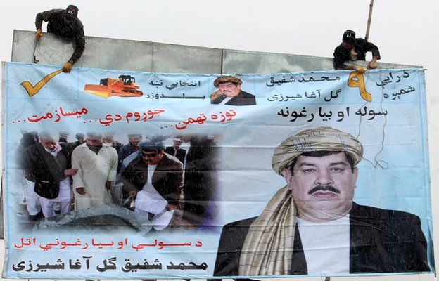 Afghan workers erect an election campaign poster of politician Gul Agha Shirzai in Kandaha