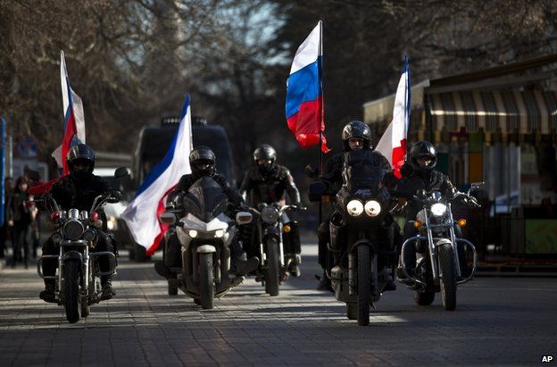 Bikers escort a van carrying the coffins of two men shot dead in Crimea, through the streets of Simferopol, 22 March