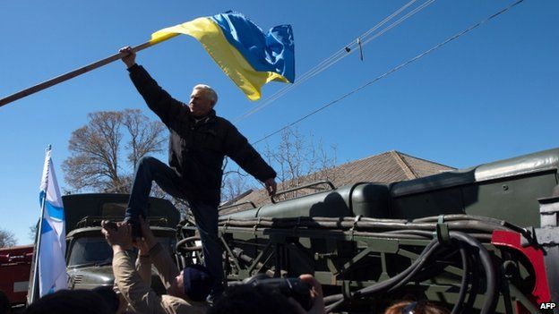 Pro-Russian protesters take down a Ukrainian flag during the storm of Novofedorivka