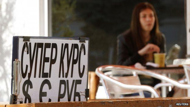 A woman sits in a cafe behind an advertising placard in Sevastopol on 24 March 2014.