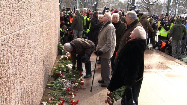 Elderly Latvians lay flowers at a war memorial in Riga