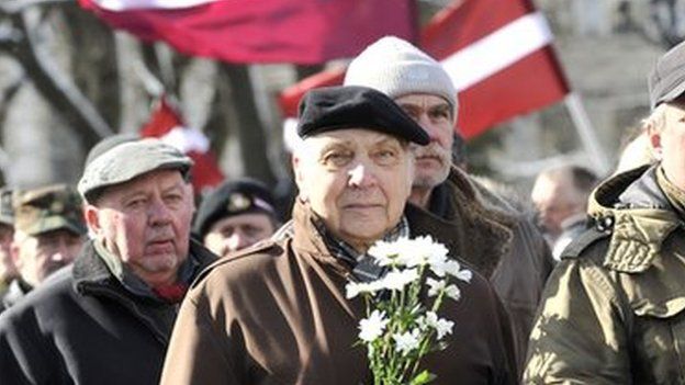 People carry Latvian flags as they march to the Freedom Monument to commemorate World War II veterans who fought in Waffen SS divisions, in Riga, Latvia, on 16 March 2014