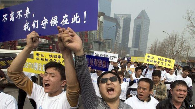 Chinese relatives of passengers onboard the missing Malaysia Airlines plane, flight MH370, shout in protest as they march towards the Malaysia embassy in Beijing, China, Tuesday, March 25, 2014