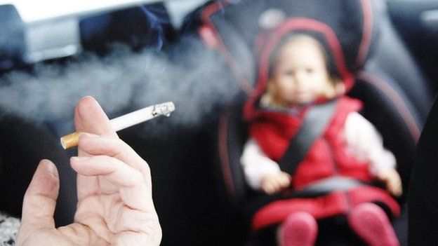 Person smoking in car with a small child in the back seat