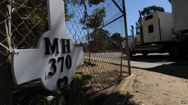 A cross and wreath in memory of those on board the lost Malaysia Airlines Flight MH370 is shown fixed to a fence surrounding Pearce Airbase