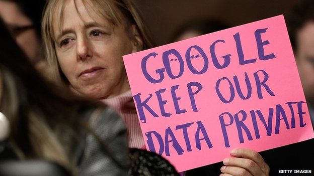 Woman displays a sign at a Senate hearing into Google activity