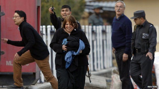 Afghan policemen evacuate foreigners from the site of the attack