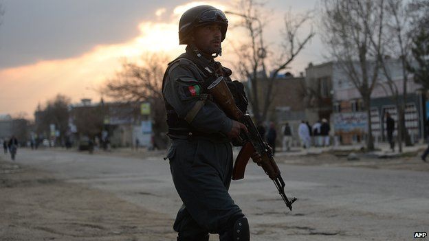 An Afghan policeman stands guard near a guesthouse attack by Taliban fighters in Kabul on March 28, 2014