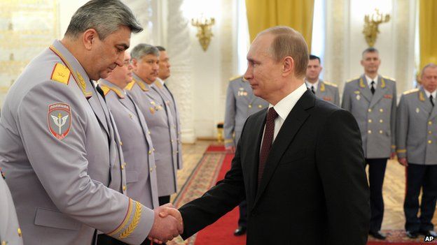 Russian President Vladimir Putin, right, shakes hands with Head of the Russian Interior Ministry's branch in the North Caucasus Kazimir Botashev at the presentation ceremony of the top military brass in the Kremlin in Moscow, Russia, Friday, March 28, 2014.
