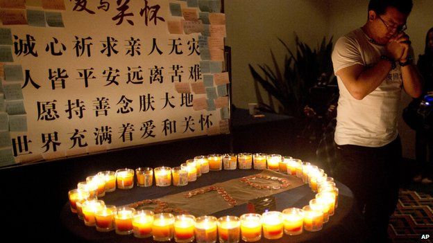 A man, a relative of a Chinese passenger on board Malaysia Airlines Flight 370, prays near candles before a briefing with Malaysian officials at a hotel in Beijing, China (March 31, 2014)