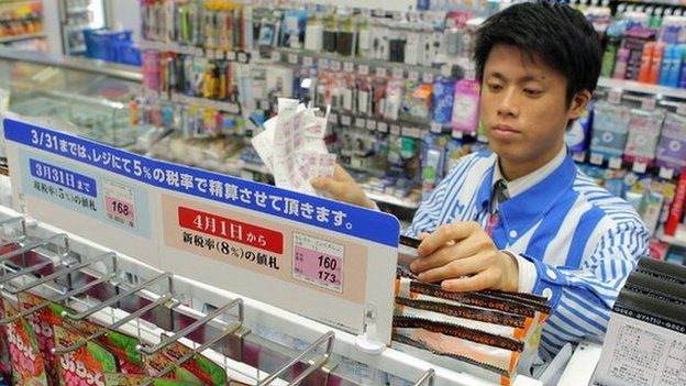 The shop manager of a convenience store updates price tags as Japan's consumption tax raises from five percent to eight percent in Tokyo on 31 March 2014