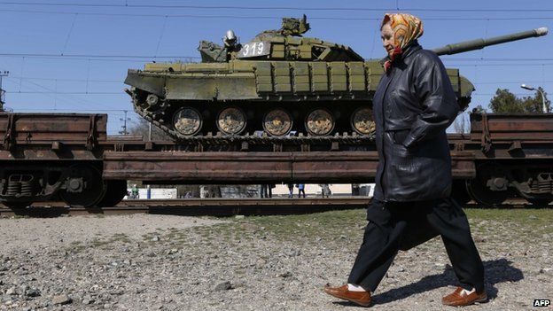 A woman walks past a trainload of Ukrainian tanks near the Crimean capital Simferopol on 31 March 2014
