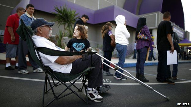 Juan Ortiz, 67, and his 18-month-old grandson wait in line at a health insurance enrolment event in Commerce, California, on 31 March 2014