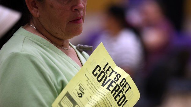 A woman holds a flier with the words "let's get covered" during a healthcare signup fair in California on 28 March.