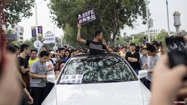A man raises a placard which reads, "Oppose PX (paraxylene petrochemicals), give me back my pure land", as he and other residents protest against a chemical plant project in Maoming, Guangdong province, 31 March 2014
