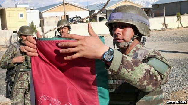 Afghan National Army (ANA) soldiers participate in a flag-lowering ceremony at Camp Maiwand on 2 April 2, 2014 near Pul-e Alam, Afghanistan