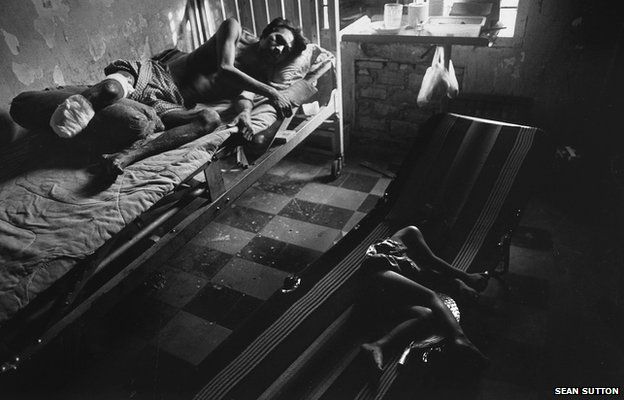 As his daughter sleeps nearby, a man lies in hospital recovering from a leg amputation following a landmines accident. Cambodia, 1996