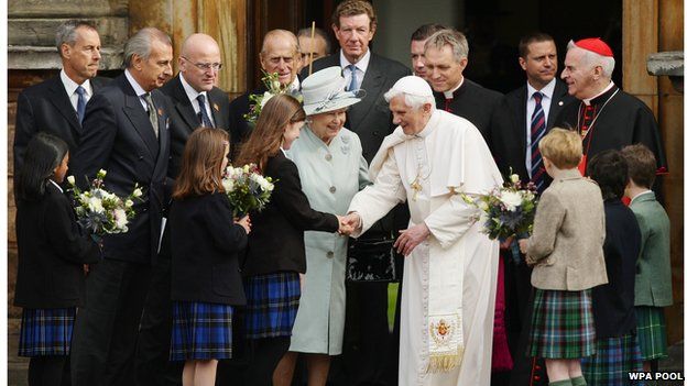 Queen Elizabeth II and Pope Benedict XVI, surrounded by other people, meet school children outside the Palace of Holyroodhouse, the Queen's official residence in Scotland, on 16 September 2010
