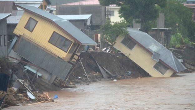 Flood waters run past damaged homes in the Solomon Islands capital of Honiara on 4 April 2014.