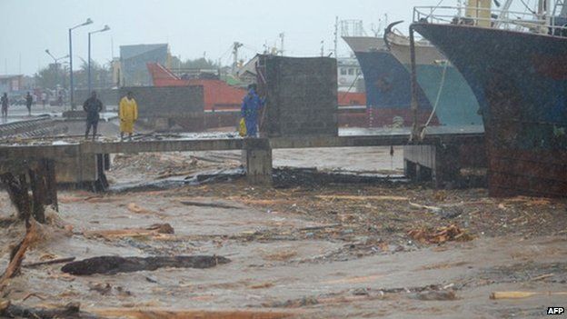 People walk past water clogged with debris at a port in the Solomon Islands capital of Honiara after flooding on 4 April 2014.