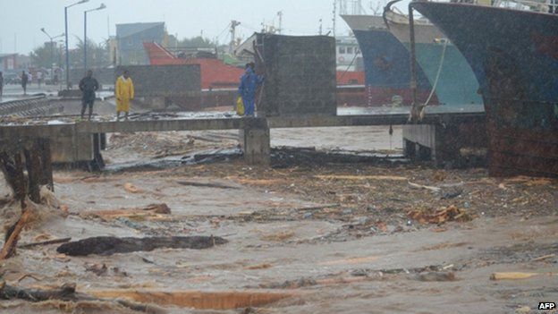 People walk past water clogged with debris at a port in the Solomon Islands" capital Honiara